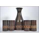 A jersey pottery carafe and four matching beakers, each with a continual geometric band,