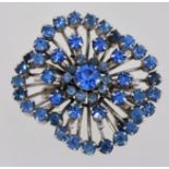 A 1950s to 1960s rhinestone brooch in two shades of blue with a silver tone setting and roll over