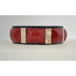 An unusual 1920s celluloid bangle, composed of pieces of printed, marbled and glittered celluloid.