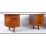 A 1970's large Danish influence teak wood desk having shaped supports with raised pedestals having