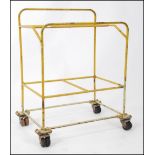 A mid century Industrial yellow metal cage trolley raised on twin wheel corner castors.