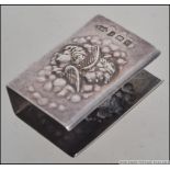A silver hallmarked matchbox cover with cherub - putti masks having monogram to the side.