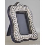 A silver rococo hallmarked miniature picture frame with velour easel backed.