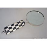 A contemporary large desk top magnifying glass with black and white chequered handle. Measures 22.