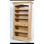 A contemporary tall open Oak bookcase having three adjustable shelves above two drawers with a