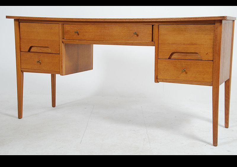 A 1970's Youngers teak wood desk raised on shaped supports having floating pedestals with recessed