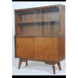 A mid century Danish influenced teak display cabinet having glazed cabinet being raised on tapered