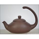 A Chinese terracotta Yi-xing teapot with unusual scrolled handle over lid.