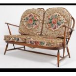 An Ercol beech and elm wood Windsor pattern two seat sofa settee raised on turned legs with