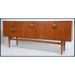 A 1970's Danish inspired retro teak wood sideboard having a bank of drawers with cupboards and fall