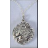 A silver Art Nouveau style locket with rococo decoration in relief set to a silver chain.