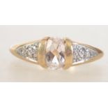 A hallmarked 9ct gold ring with central clear oval cut gemstone with illusion set diamond chip