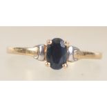 A 9ct gold ring set with an oval cut sapphire with white gold accent shoulders. Tests 9ct gold.