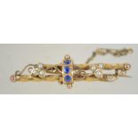 An Edwardian 9ct gold blue stone and pearl brooch with filigree scroll decoration having a c clasp