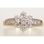 A 9ct gold and diamond ring with central diamond cluster and channel set diamond shoulders.