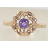 A hallmarked 9ct gold and amethyst ring set with a central amethyst within a scroll setting.