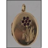 A hallmarked 9ct gold locket with flower decoration to front set with a cluster of garnets.