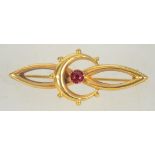 An early 20th century 9ct gold bar brooch with crescent moon and set red stone with C clasp.