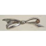 A silver brooch in the form of a bow with roller clip clasp. Marked Silver. Measures 2 1/4 inches.