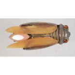 A vintage cicada brooch having rhinestones a peach opalescent glass body and amber glass wings with