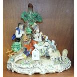 A large Sitzendorf figure group depicting a courting couple sitting beside a tree, she playing a