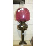 A brassed oil lamp with reeded column and purple glass shade, 72cm high overall.