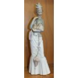 A Lladro figurine of a young lady carrying a Pekinese dog, 37cm high, (a/f).