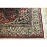 A large rug decorated with stylised flowers within the border and the central red ground, 275 x