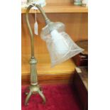 A brass desk lamp with reed column on four shaped feet, with clear glass shade, 47cm high.