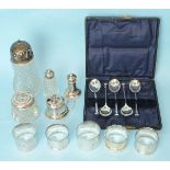 Five various silver napkin rings, a silver topped cut glass sugar caster and other small silver,