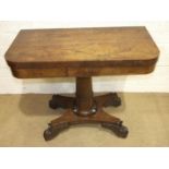 A George IV rosewood fold-over card table, the rectangular top on a tapered and carved column and