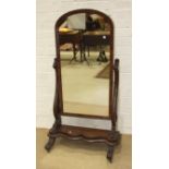 A Victorian mahogany cheval mirror of plain arched form, with pierced scroll supports, on serpentine