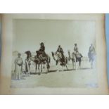 A 9" x 11" sepia photograph of four men on camels, 'Chanlier des caravan a Kantara', an early-20th