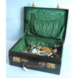 A leather-bound travelling vanity case, the green silk-lined interior containing four silver-