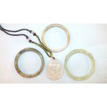 A modern carved jade pendant on braid necklace and three Chinese jade bangles, (interior diameter