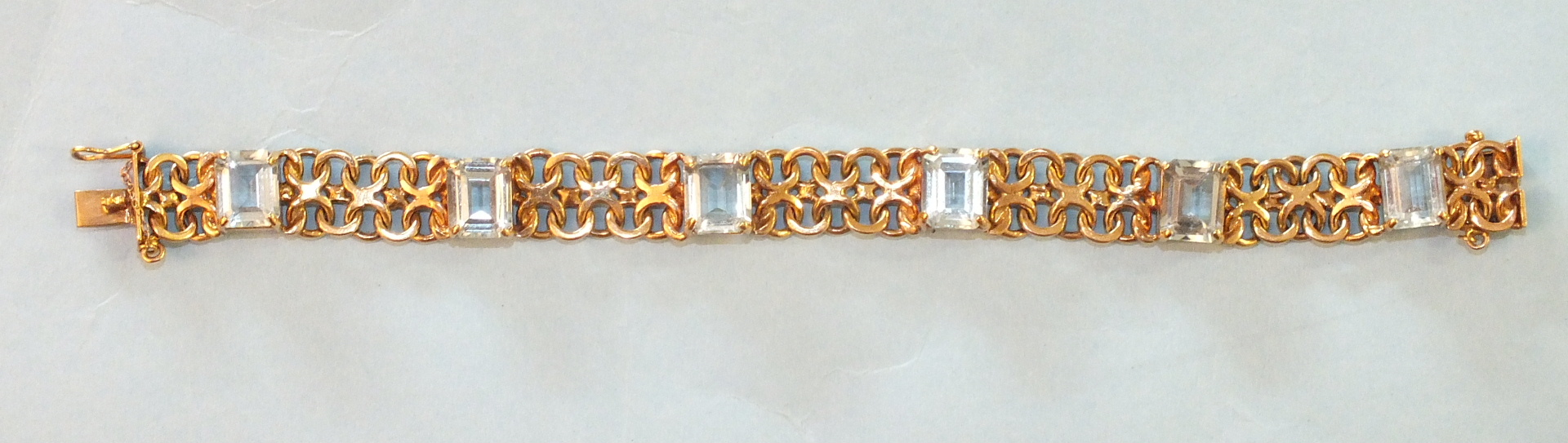 A 9ct gold bracelet of figure of eight links, claw-set six step-cut aquamarines, each