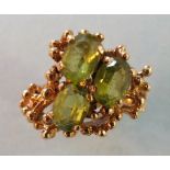 A 9ct gold ring of abstract design set three peridot stones, size J, 5.8g.