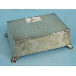 A silver cigarette case of canted rectangular form on bracket feet with engine-turned lid, 16 x