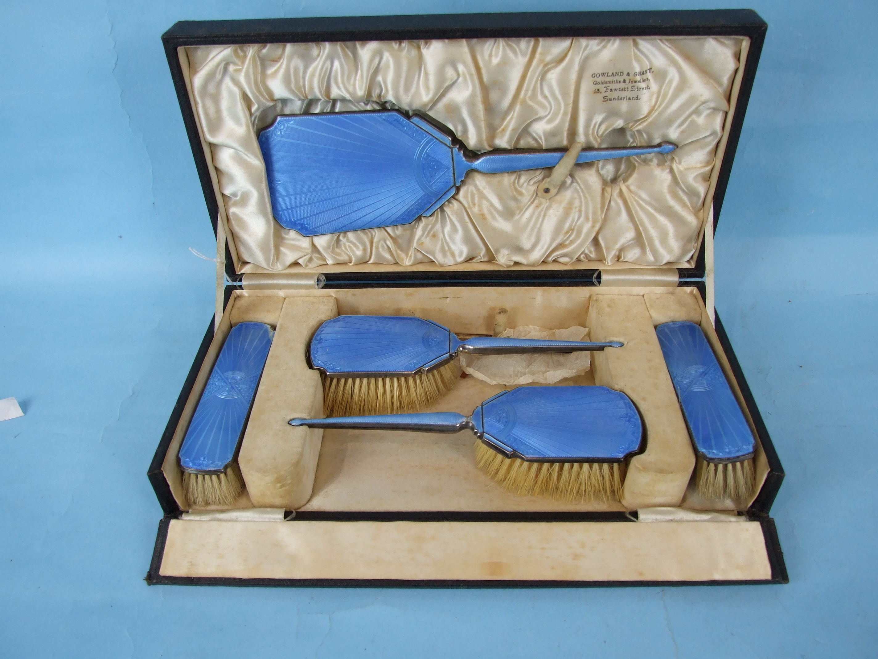 A cased blue enamelled silver dressing table set by Gowland & Grant, comprising four brushes and