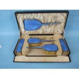 A cased blue enamelled silver dressing table set by Gowland & Grant, comprising four brushes and