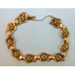 A 9ct gold bracelet of ten lyre-shaped motifs, each collet-set a round-cut peridot, with concealed