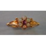 A Victorian 18ct gold ring set flower head cluster of six opals around a round cut garnet, (one opal
