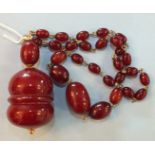 A very large cherry red Bakelite amber pendant of baluster form, with yellow metal mounts and a
