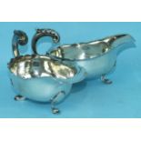 A pair of silver sauce boats, each with shaped rims, flying scroll handles and three feet,