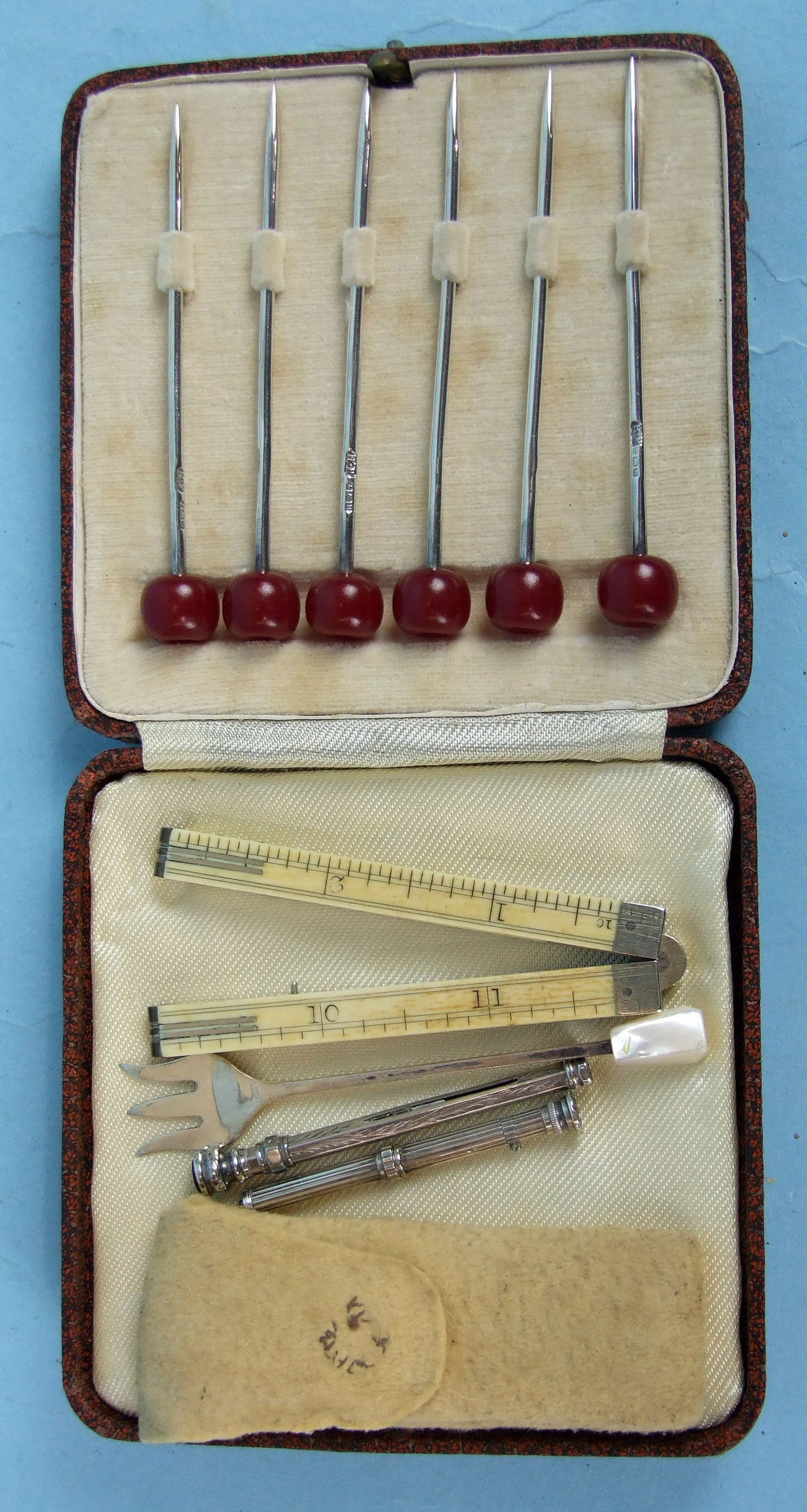 A cased set of six silver cocktail sticks, Birmingham 1932, a miniature silver pickle fork, a