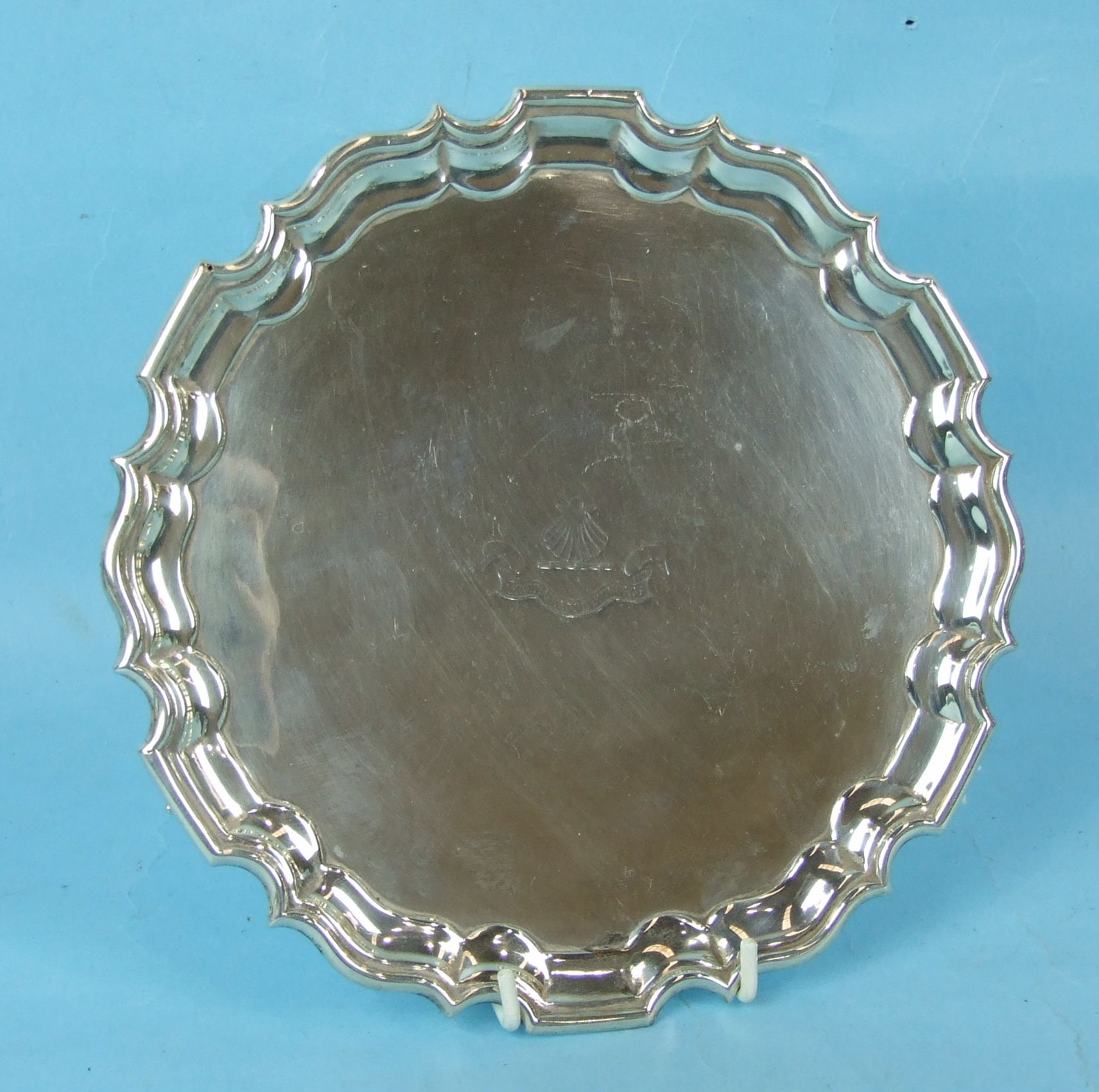 A late Victorian small silver salver with Chippendale border, raised on leaf capped scroll feet,