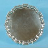A late Victorian small silver salver with Chippendale border, raised on leaf capped scroll feet,