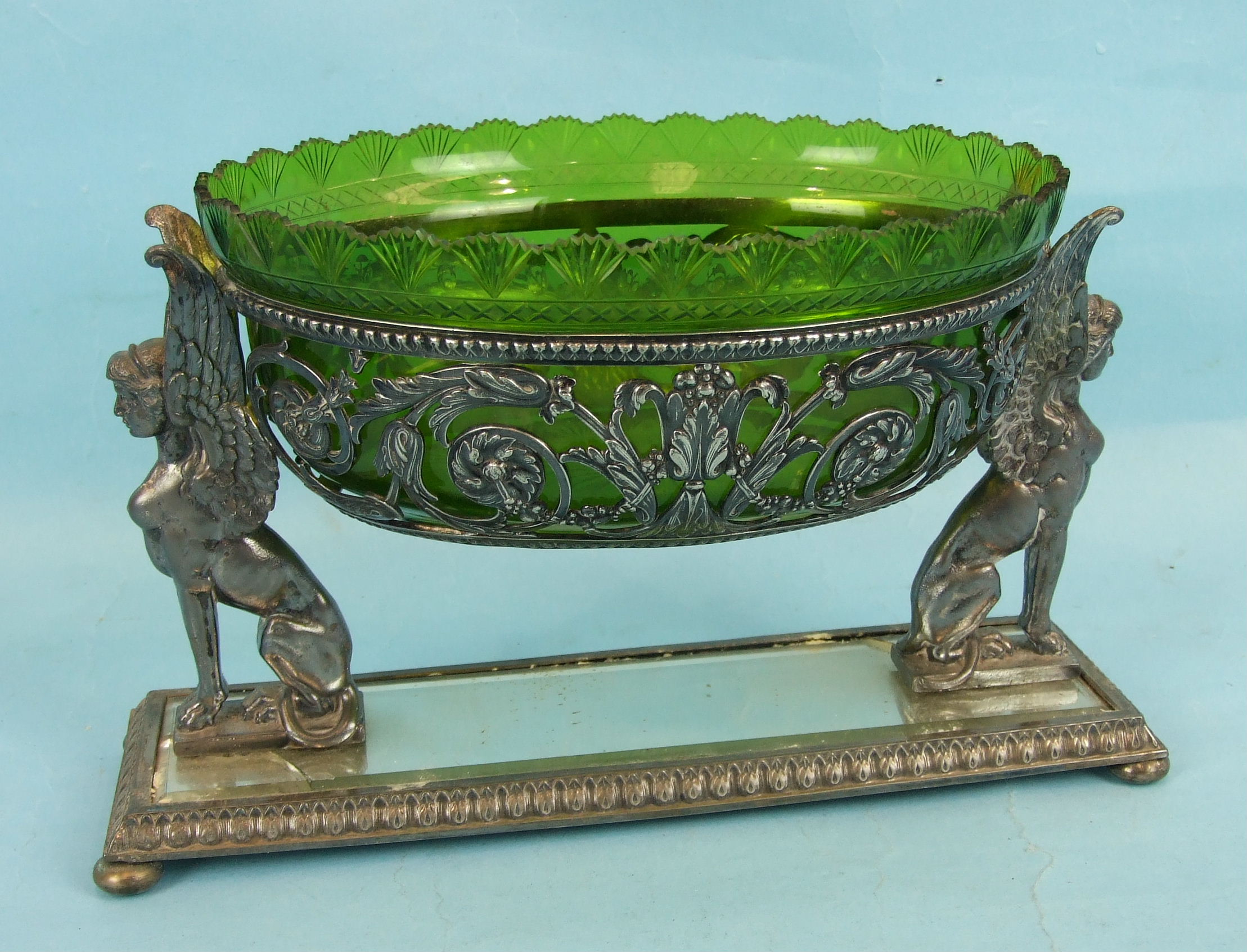 A WMF oval foliate pierced fruit bowl with green glass liner supported by two sphinges on mirrored