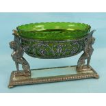 A WMF oval foliate pierced fruit bowl with green glass liner supported by two sphinges on mirrored