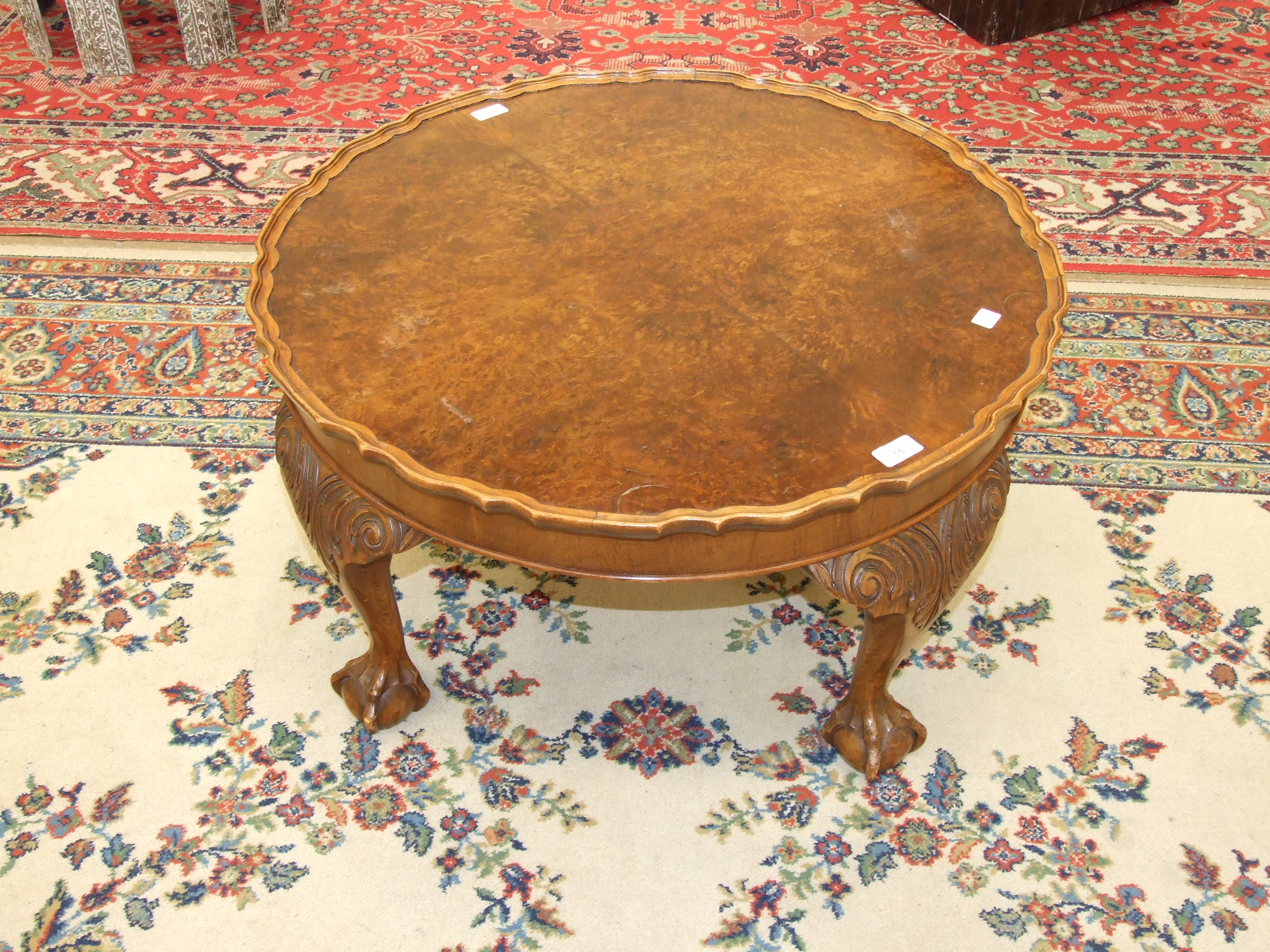 A walnut circular coffee table on four carved wood legs, with claw and ball feet, 74cm diameter,